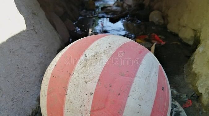 Jovens tentam resgatar bola em córrego, comemoram recuperação, mas ela volta para o esgoto